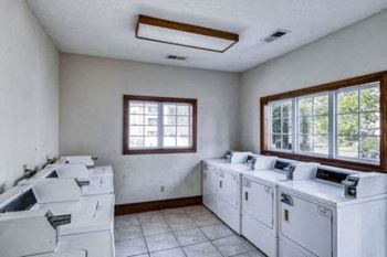 an empty laundry room with white appliances and windows